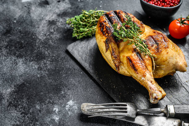 istock Grilled whole organic chicken with thyme. Black background. Top view. Copy space 1256581535