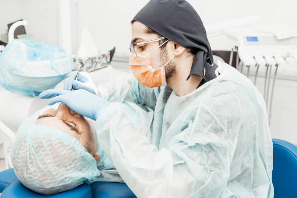 istock Patient and dentist during implant placement operation. Real operation. Tooth extraction, implants. Professional uniform and equipment of a dentist. Healthcare Equipping a doctorâs workplace. Dentistry 1256584371