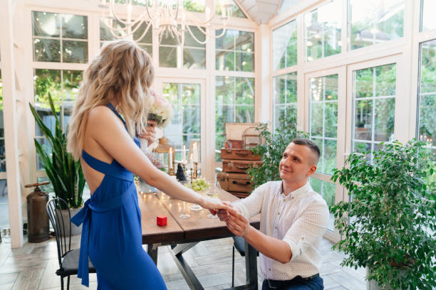 istock man putting engagement ring on finger girl. 1256585528