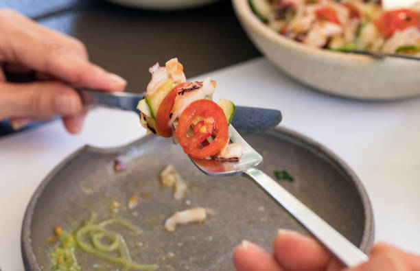 istock Human hand holding a fork with food over a plate 1256590357