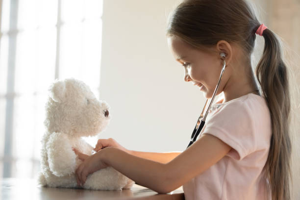 istock Smiling little girl using stethoscope, playing with fluffy toy 1256590445