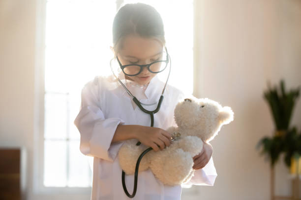istock Close up pretty little girl playing doctor, using stethoscope 1256590459