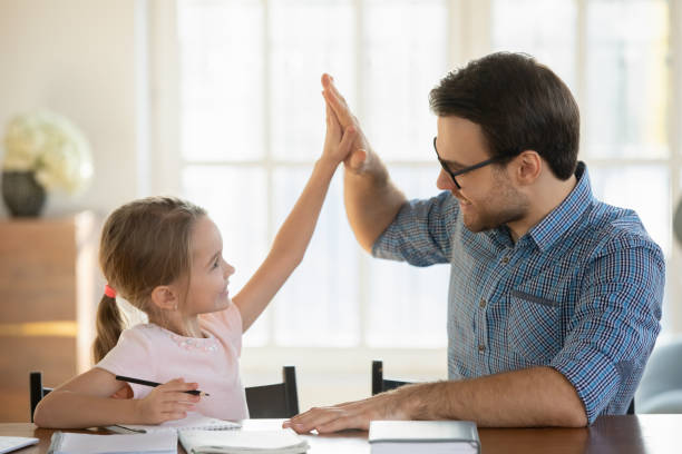 happy little girl and father giving high five, studying together - junior high fotos imagens e fotografias de stock