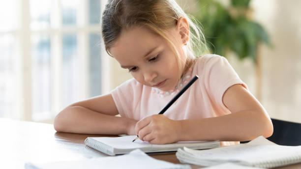istock Close up focused little girl drawing with pencil in notebook 1256590482