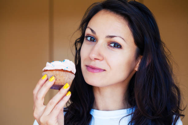 istock Young woman eating a cupcake 1256591668