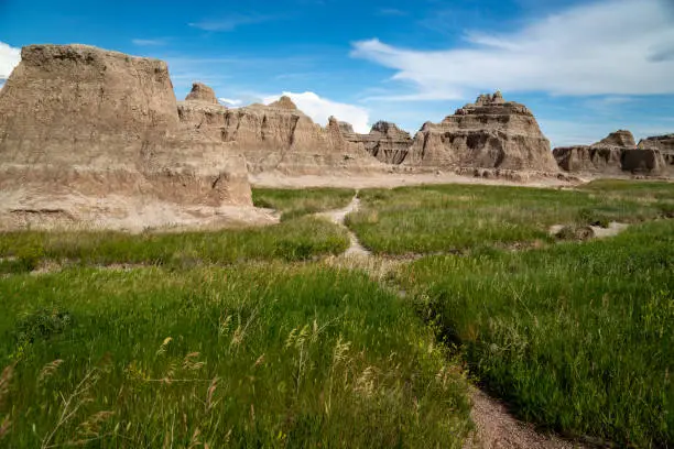 Photo of The Notch, Door and Window area of Badlands National Park, with green grass in foreground. South Dakota, USA