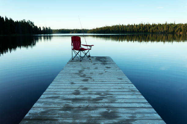 Black lake is a hidden Gem,  Part of Nopiming Provincial Park, Manitoba , Canada.  Two hour drive NE of Winnipeg.  Boat launch with red chair and fishing rod. Image taken from a tripod.
