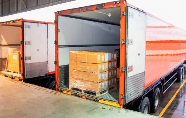 Photo of Road freight warehouse industry logistics and transportation. Truck loading cargo shipment goods into container truck.
