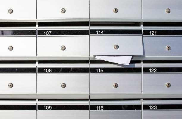 Letterboxes for apartments, with mail sticking out of one Letterboxes for apartments, with mail sticking out of one of the open letterboxes wide screen stock pictures, royalty-free photos & images