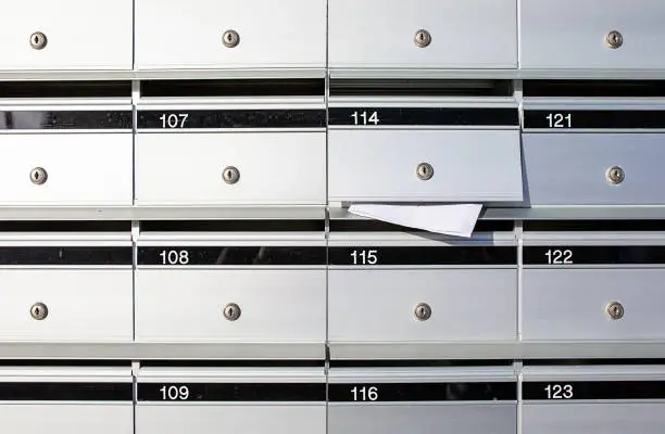 Letterboxes for apartments, with mail sticking out of one of the open letterboxes