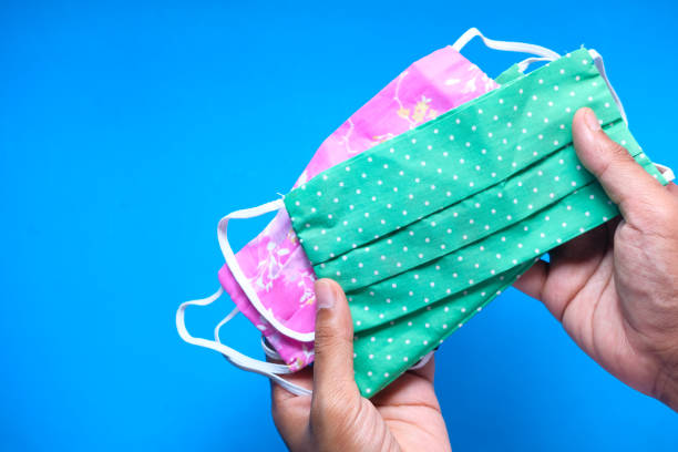 istock man hand holding homemade protective mask on blue background 1256605947
