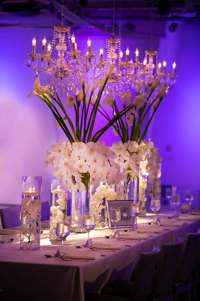 istock Wedding table with blue ambient lighting and white flower decor with floating candle containers 1256612549
