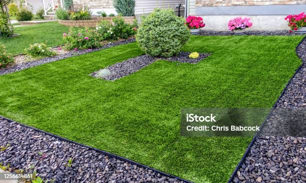 A Beautiful Artificial Lawn In The Front Yard With Nice Flowers And Shrubs Surrounding It Stock Photo - Download Image Now