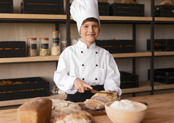 istock Little baker cutting bread and smiling 1256619291
