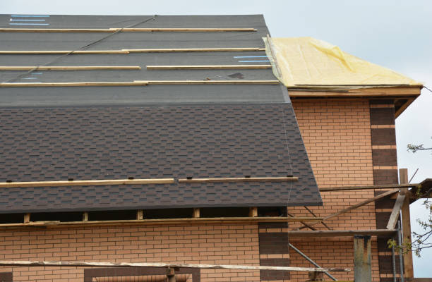 a close-up on a roofing construction with asphalt roof shingles installed on the waterproof underlayment and uncovered roof sheathing of incomplete house construction with scaffoldings. - bitumen felt imagens e fotografias de stock