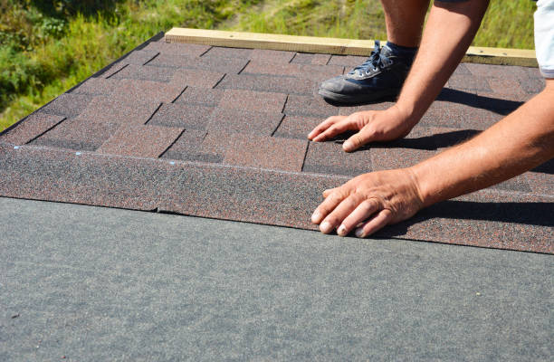 a building contractor is installing dimensional asphalt roof shingles on the underlayment of the house construction repairing the rooftop. - bitumen felt imagens e fotografias de stock