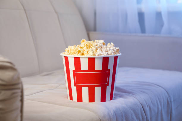 istock Bucket of popcorn on sofa. Watching films home 1256621982