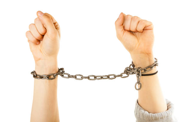 istock Chained man hands with chain around wrists 1256622066