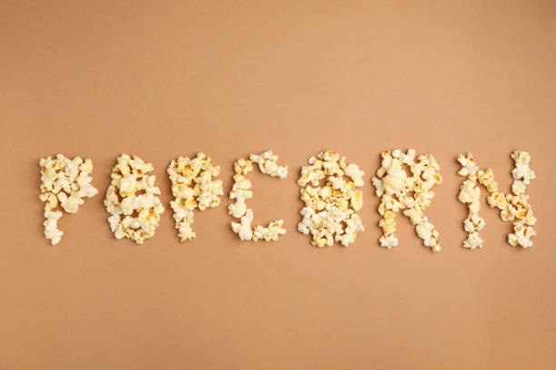 istock Text Popcorn on brown background, top view. Food for cinema 1256622123
