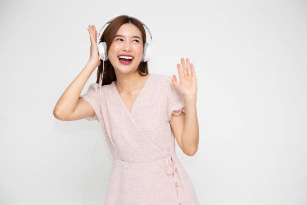 joven asiática escuchando música con auriculares aislados sobre fondo blanco - samba dancing audio fotografías e imágenes de stock