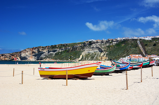 Beach in Nazare with traditional colorful boats, Portugal. Composite photo