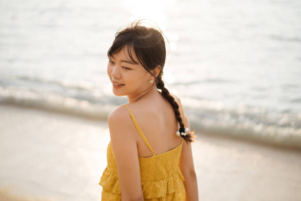 istock Young asian female tourist with sun hat having fun at beach 1256631443