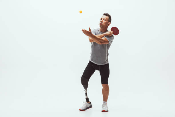 istock Athlete with disabilities or amputee isolated on white studio background. Professional male table tennis player with leg prosthesis training and practicing in studio. 1256634589