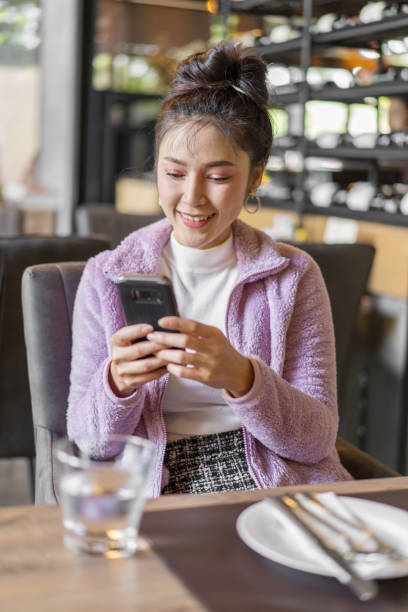 istock woman using smartphone in restaurant 1256638613