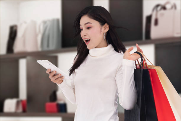 istock surprised woman shopping and using digital tablet at mall 1256638620