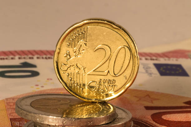 istock Close up of a 20 euro cent coin standing between other coins and notes 1256643892