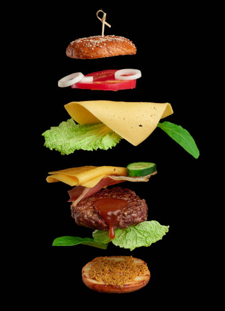 levitating cheeseburger ingredients: juicy meat cutlet, cheddar cheese, sesame bun, lettuce, white onion rings, slice of tomato, cucumber levitating cheeseburger ingredients: juicy meat cutlet, cheddar cheese, sesame bun, lettuce, white onion rings, slice of tomato, cucumber on black background. Fast food floating in the air levitation stock pictures, royalty-free photos & images