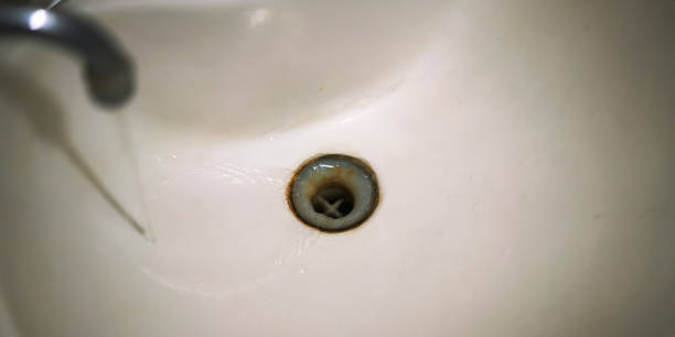 istock water runs from silver tap into white sink with rusty drain 1256647714