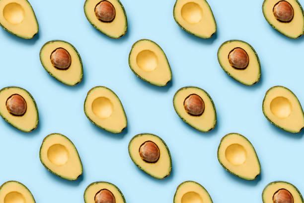 istock Pattern of halves of avocado on a blue background 1256649485