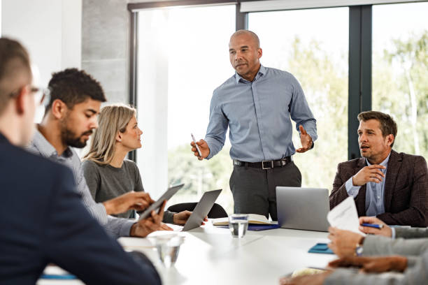 African American CEO talking to his team on a meeting in the office. Mid adult black businessman giving a speech to his colleagues during a meeting in the office. business meeting stock pictures, royalty-free photos & images
