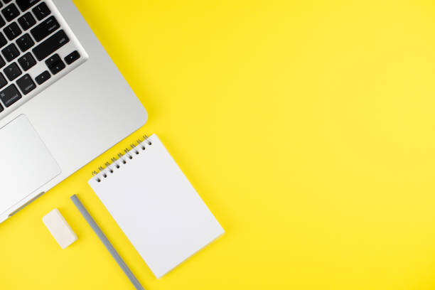 istock Laptop, notepad planner with gray pencil and erase rubber on yellow background. Flat lay. Copy space. Workplace in the office. 1256653053