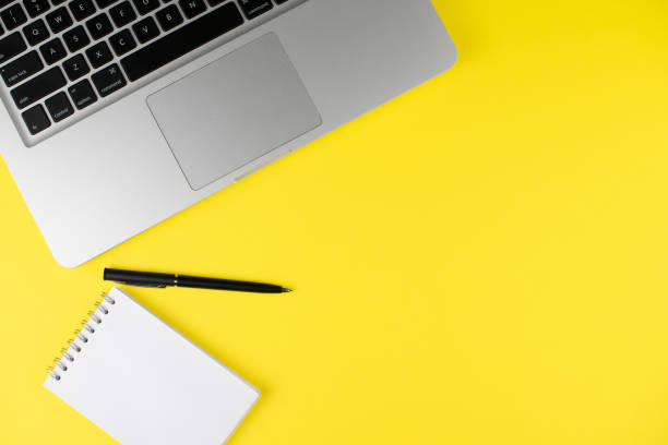 istock Laptop, notepad planner with black pen on yellow background. Flat lay. Copy space. Workplace in the office. 1256653055