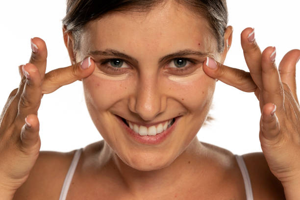 istock a young woman applies concealer under her eyes 1256653673