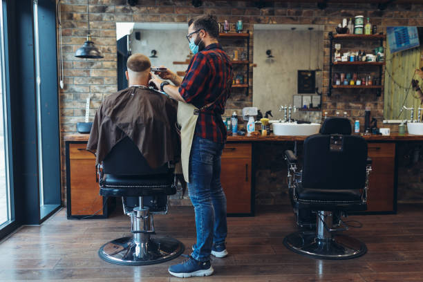 haarschnitt während der pandemie. junge männer haben haare schneiden im friseurgeschäft während der pandemie-isolation, beide tragen schutzausrüstung. - hair care beauty caucasian preparation stock-fotos und bilder