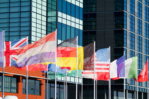 International flags at office buildings in modern harbor of Amsterdam at street Piet Heinkade