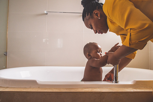 Boy in a bath tub being helped by his mother