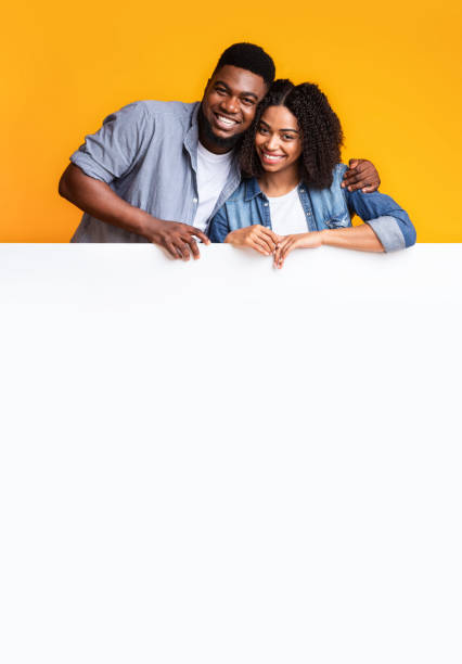 istock Empty Space For Advertisement. Black couple leaning on white board and hugging 1256667244