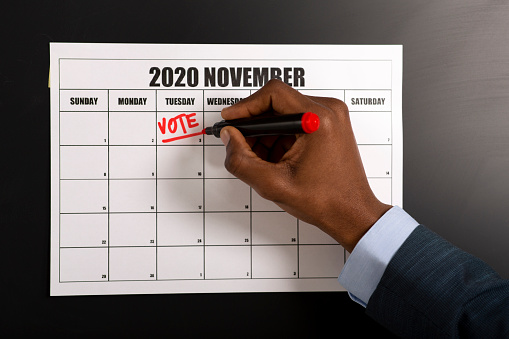 African american businessman writing Vote on November 3, 2020, presidential elections, patriotic concept