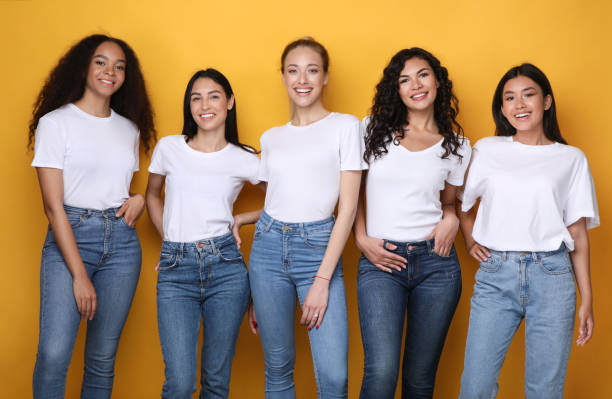 Five Multiethnic Models Girls Smiling Standing In Studio, Yellow Background Five Multiethnic Models Girls Smiling To Camera Posing Standing In Studio On Yellow Background. Female Diversity Concept japanese girlfriends stock pictures, royalty-free photos & images