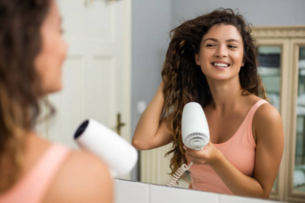 Woman using hairdryer Young woman with gorgeous  curly hair using hairdryer. blow drying stock pictures, royalty-free photos & images