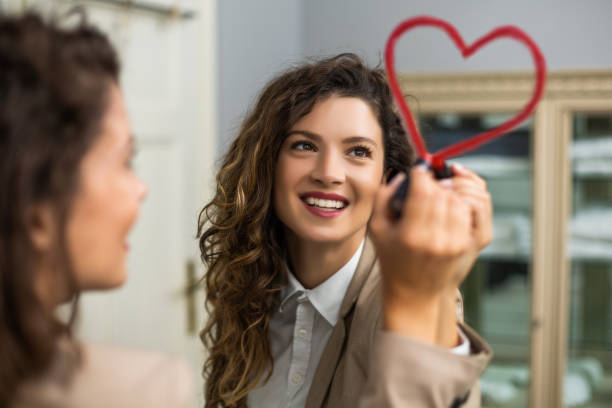 Woman drawing heart with lipstick on the mirror stock photo