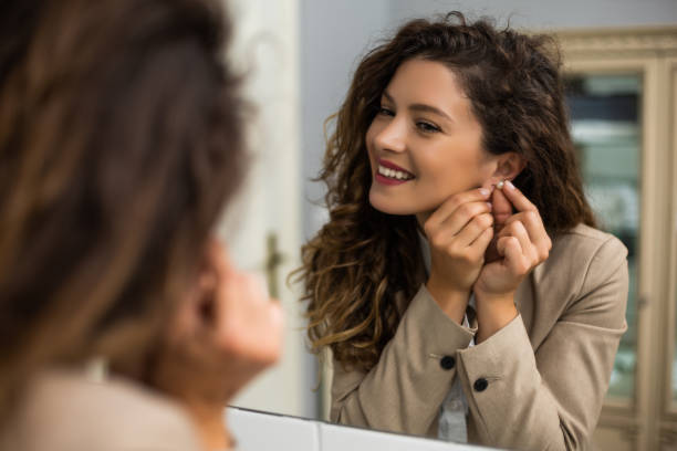 woman putting earrings - mirror women bathroom make up imagens e fotografias de stock