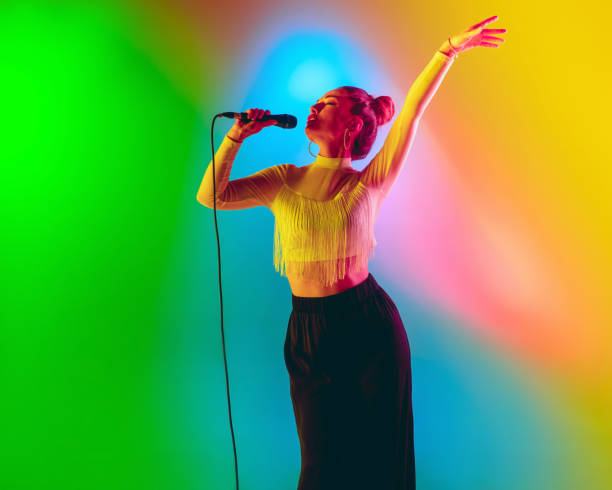 istock Young caucasian musician playing, singing on gradient background in neon light. Concept of music, hobby, festival 1256673881
