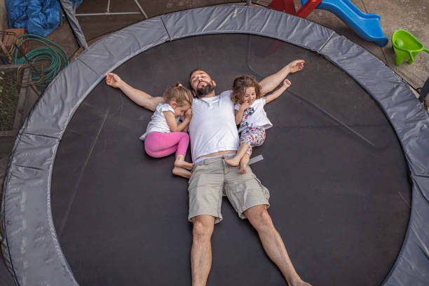 istock Father and his two little daughters are lying on a trampoline 1256675209