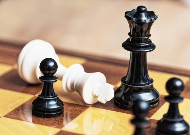Fallen king symbolizes white's resignation in a chess game.