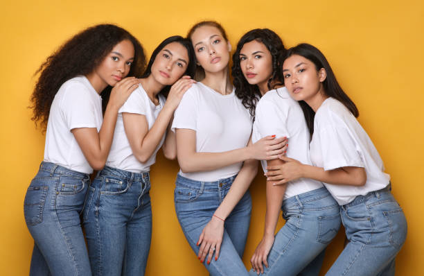 istock Sensual Multiethnic Girls Hugging Posing Over Yellow Studio Background 1256676606